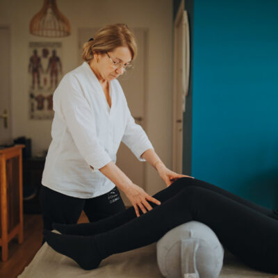Praticienne de Shiatsu appliquant des pressions sur les jambes d'une cliente allongée