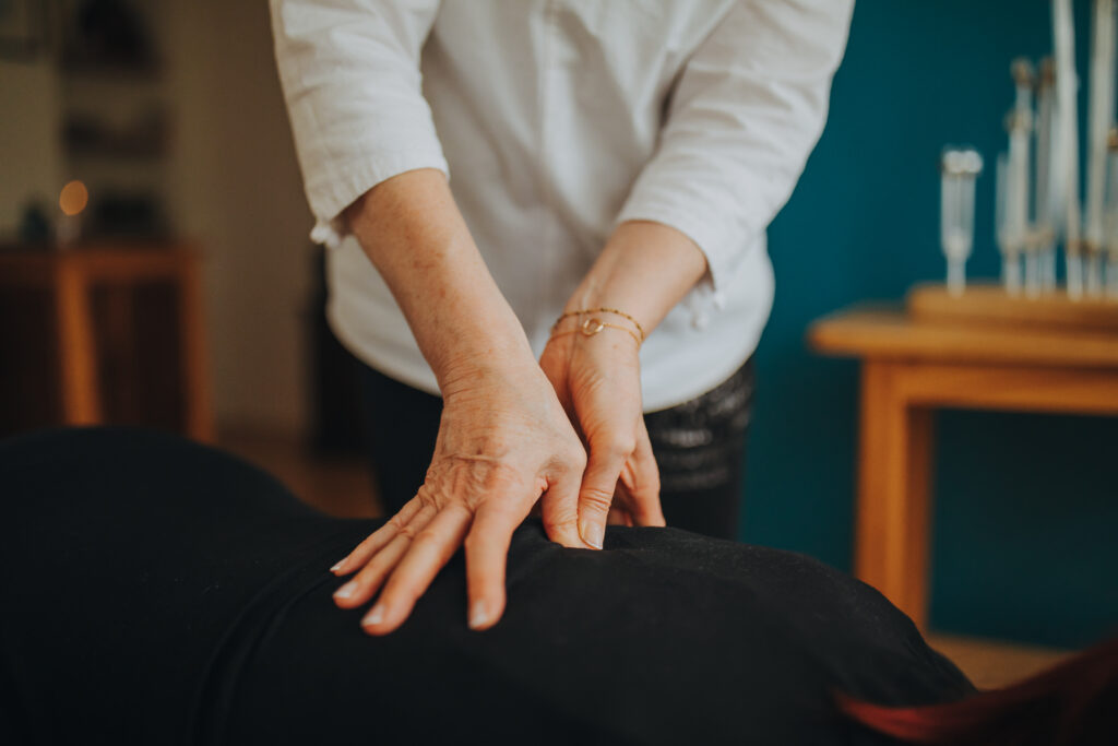 Doigts du praticien appliquant une pression shiatsu sur le dos d'un client.
