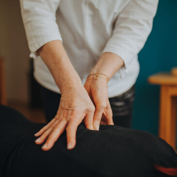 Doigts du praticien appliquant une pression shiatsu sur le dos d'un client.